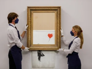 Sotheby’s employees install Banksy’s shredded painting “Love is in the Bin” at Sotheby’s in September 2021